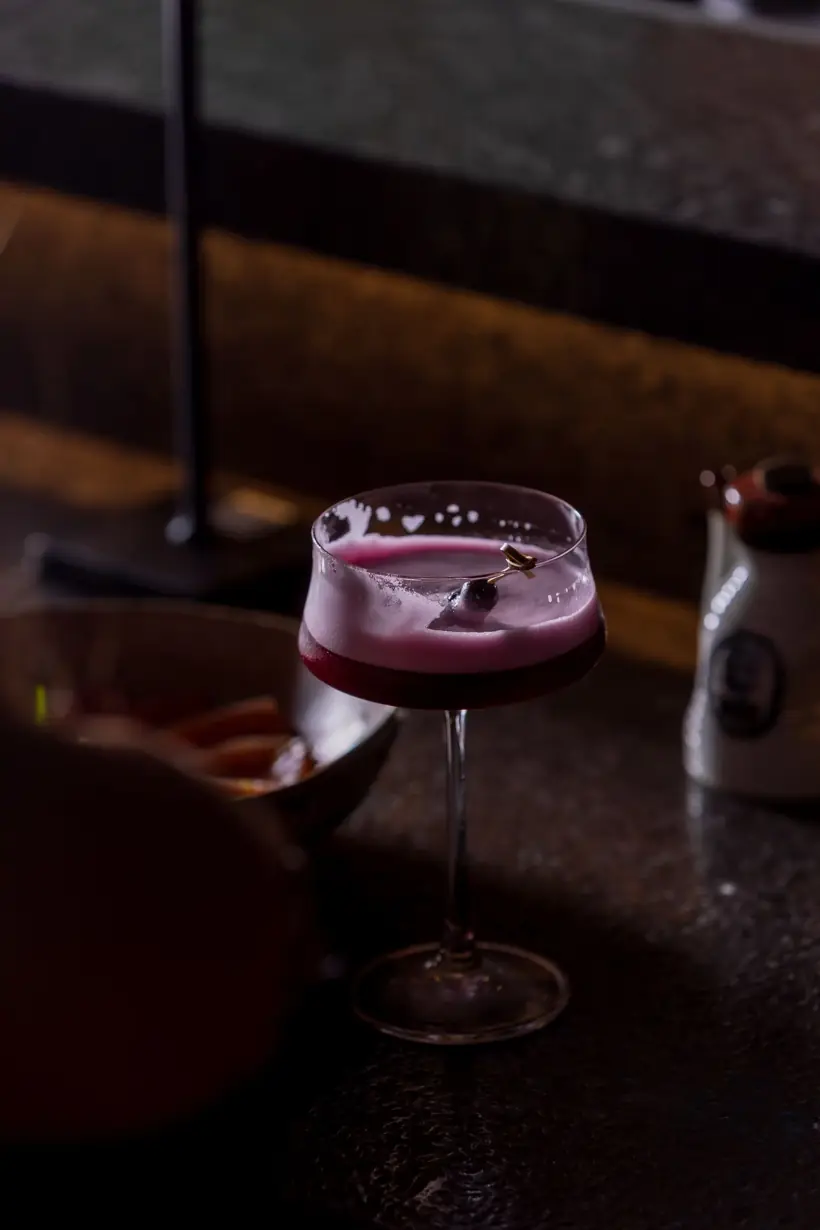 Drink roxo com espuma em taça coupe